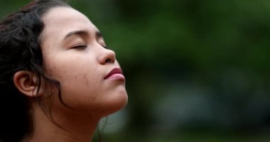 Genç kadın, meditasyon ve tefekkürde gözlerini açarak gökyüzüne umutla ve inançla bakıyor.