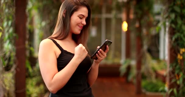 Woman Celebrates Good News Fist While Looking Cellphone Screen — Stockvideo