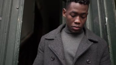 Black steps out front home door putting scarf preparing for the cold