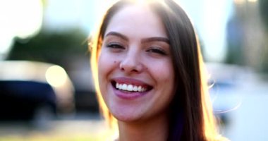 Young woman portrait smiling with lens-flare outside. Millennial girl real life smile and laugh outdoors sunflare