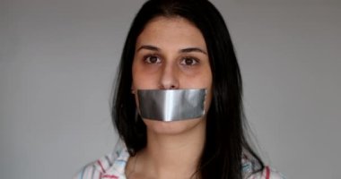 Silenced young woman having her voice shut mouth taped
