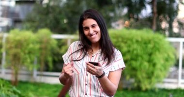 Happy young woman celebrates after good news holding cellphone