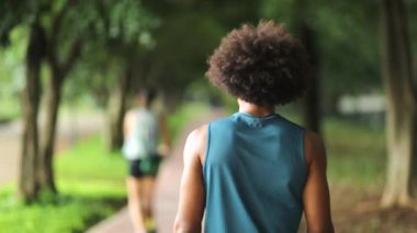 Person walking in city park road, young black man walking outside