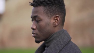 Thoughtful African black man standing outside at park thinking