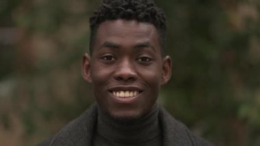 Gülümseyen mutlu siyah Afrikalı adam kış mevsiminde dışarıda duruyor.