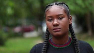 Genç siyah kadın kameraya bakıyor. Parktaki ciddi Afrikalı kız portresi