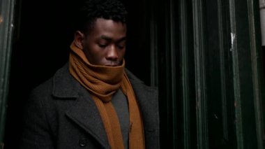 Elegant black man opening home door steps outside in the cold adjusting clothes