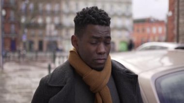 Thoughtful African man walking in sidewalk in the cold winter season