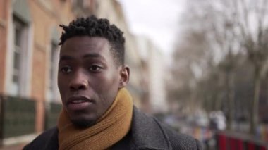 Young elegant black African man walking outside in city sidewalk