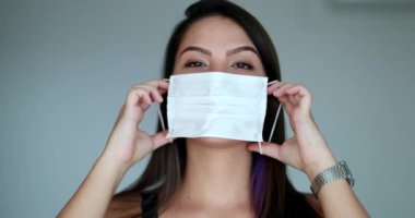 Young woman putting virus mask prevention. Attractive girl wearing covid mask looking at camera