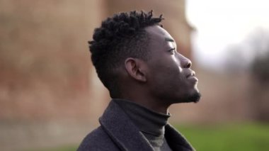 Contemplative young african black man standing looking at sky with hope and faith