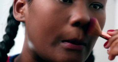 Black girl applying make-up in front of mirror. Young African woman applies makeup casual