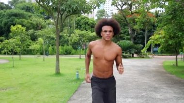 Afrikalı Amerikalı adam parkta ağır çekimde koşuyor.