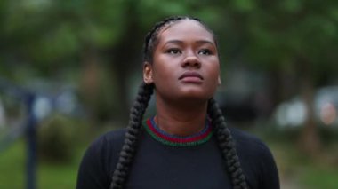 Düşünceli Afrikalı genç bir kadın doğa parkında yürüyor.