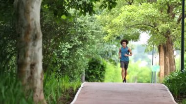 Genç siyah adam parkta koşuyor.