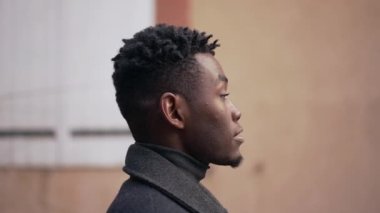 Pensive black African man standing outdoors looking at camera. contemplative person