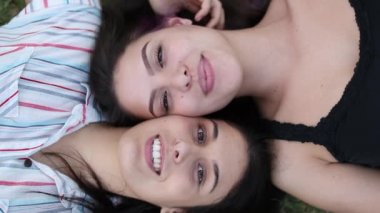 Girlfriends smiling to camera on grass outdoors