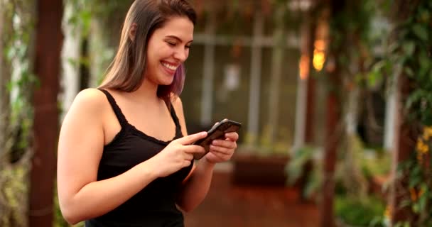 Young Millennial Woman Smiling Laughing While Holding Smartphone Device — 图库视频影像
