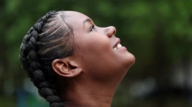 Young African woman face in contemplation loooking up at the sky with hope and faith