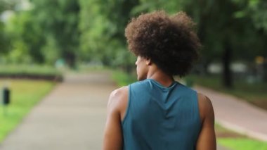 African man walking at park during light drizzle, casual