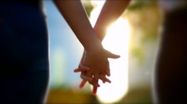 Joining hands together in sunlight flare. Close-up of two people uniting for a cause