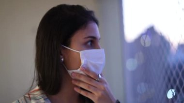 Young woman wearing surgical mask prevention against virus spread indoors, girl looking at camera