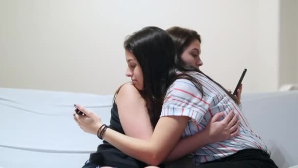 Two Girlfriends Embrace While Looking Cellphones Teenage Friends Staring Smartphone — Vídeo de Stock