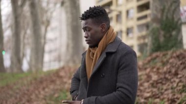 Pensive thoughtful African black man standing outside at park thinking about life