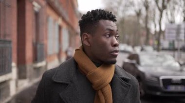 Elegant young black man walking in sidewalk during winter season exploring city or commuting