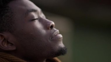 Siyah adam derin bir nefes alıyor gözlerini kapıyor ve meditasyon yapıyor.