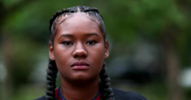 Kararlı genç zenci kadın kameraya bakıyor ve yumruğunu kaldırıyor.