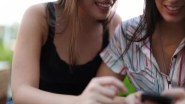 Millennial girls using cellphones. Two female friends checking smartphone communication