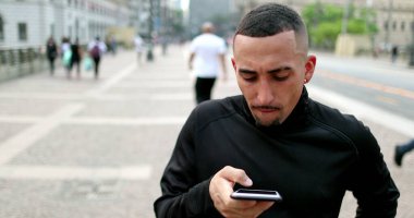 Hispanic casual person using smartphone in downtown city