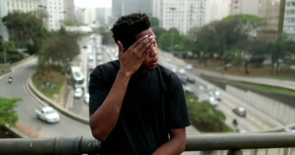 Stressed black African man standing in downtown city feeling anxiety