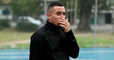 Hispanic man touching face and nose outside, walking towards camera