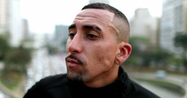 Troubled hispanic man thinking. Thoughtful worried guy in city