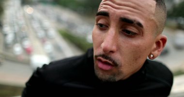 Troubled hispanic man feeling anxious in city, person suffering in pain