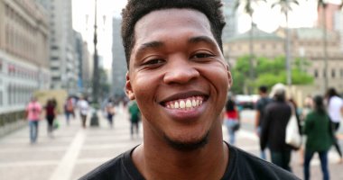 Trendy young black African man smiling at camera in downtown city, real people