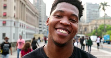 Trendy young black African man smiling at camera in downtown city, real people