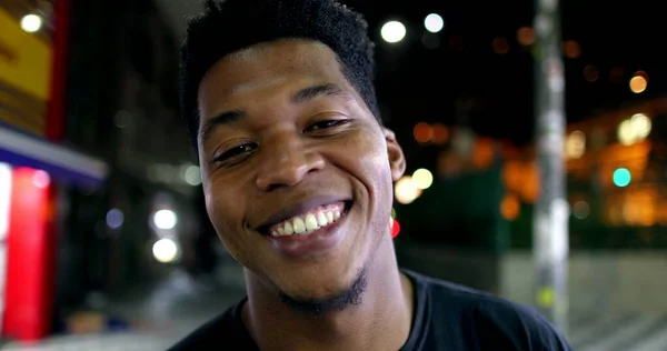 Young black man smiling looking at camera at night in city