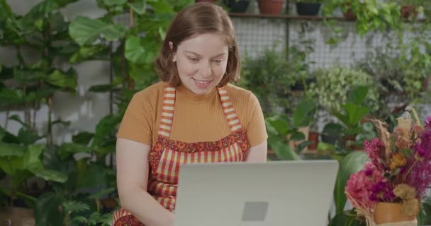 Молодой Флорист Предприниматель Проверяет Онлайн Заказы Улыбаясь Перед Ноутбуком Концепция — стоковое видео