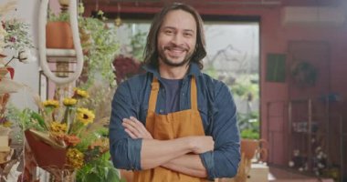 Portrait of a male staff wearing apron standing inside small business store looking at camera smiling