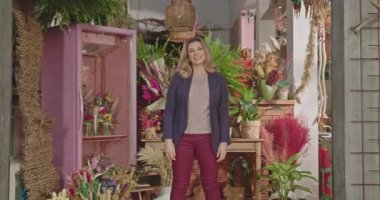 Businesswoman owner of local flower store standing in front of business. Portrait of a female entrepreneur smiling at camera