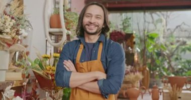Casual male worker of retail store smiling at camera with arms crossed wearing apron. Portrait of happy employee inside local flower shop
