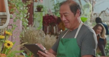 Small business owner using tablet managing online orders inside retail store. Portrait of an Asian American entrepreneur working happy with successful new business. Small business owner receiving online orders
