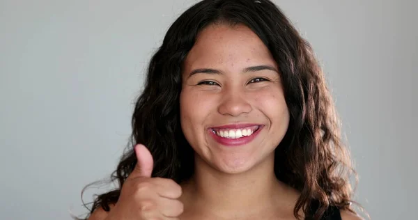 Confident hispanic girl gives thumb up to camera