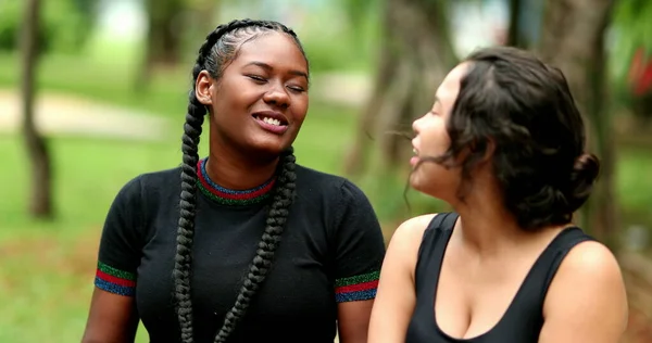 Candid female friends talking outside, real life laugh and smile