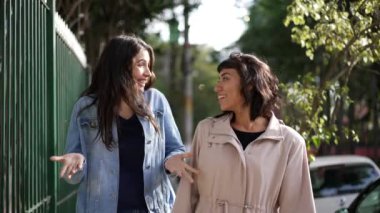 Sokakta yürürken kadınlar konuşuyor. Şehir kaldırımında sohbet eden iki kız arkadaş.