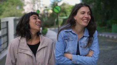 İki mutlu genç kız arkadaş sokakta birlikte gülüp gülüyorlar.