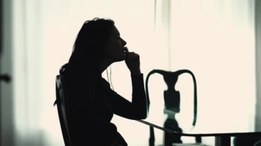 Silhouette of suffering woman sitting at home in mental pain